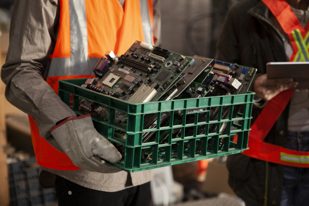 Male And Female Recycling Coworkers Holding Digital Tablet And Plastic Box Full Of Mother Boards