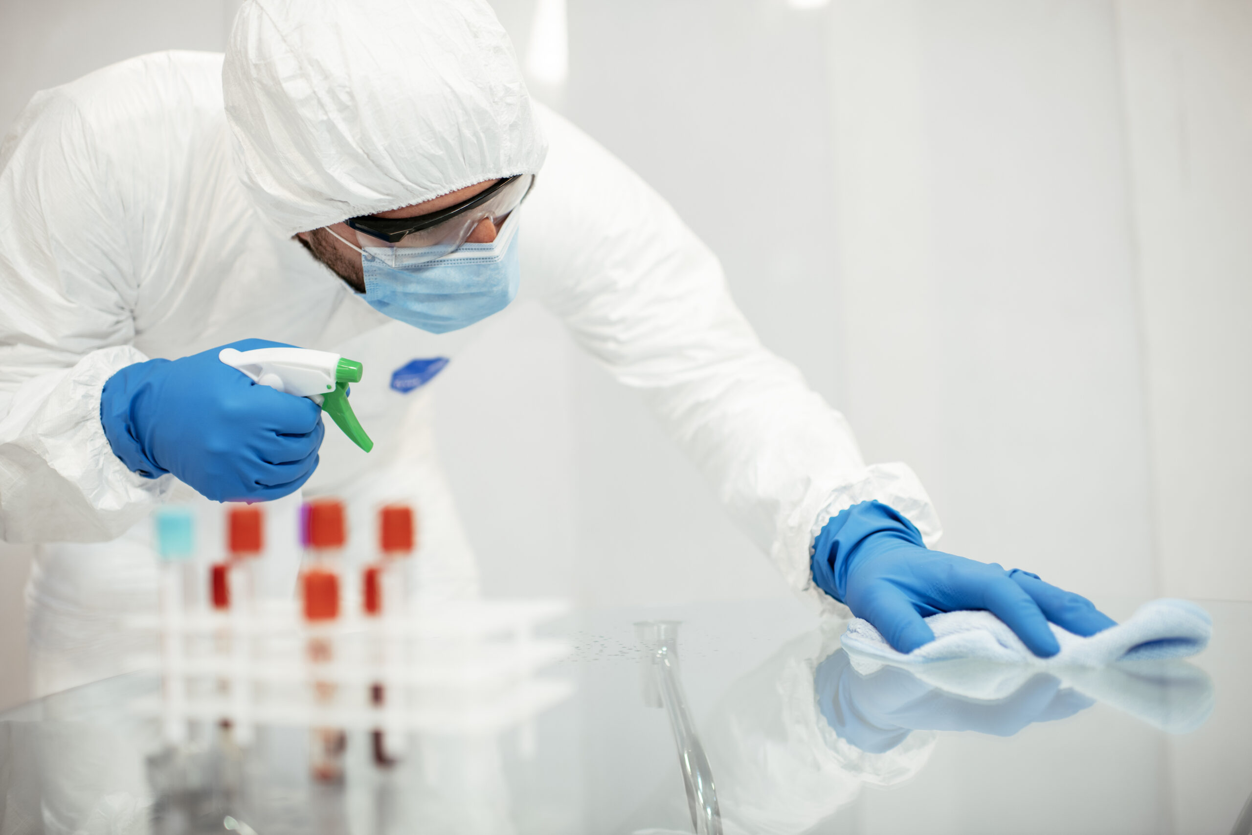 Covid 19 Wiping Down Surfaces. Man With Gloves And Disinfectant Wipe Sanitizing The Desk To Prevent Germs And Bacteria Infections Stock Photo